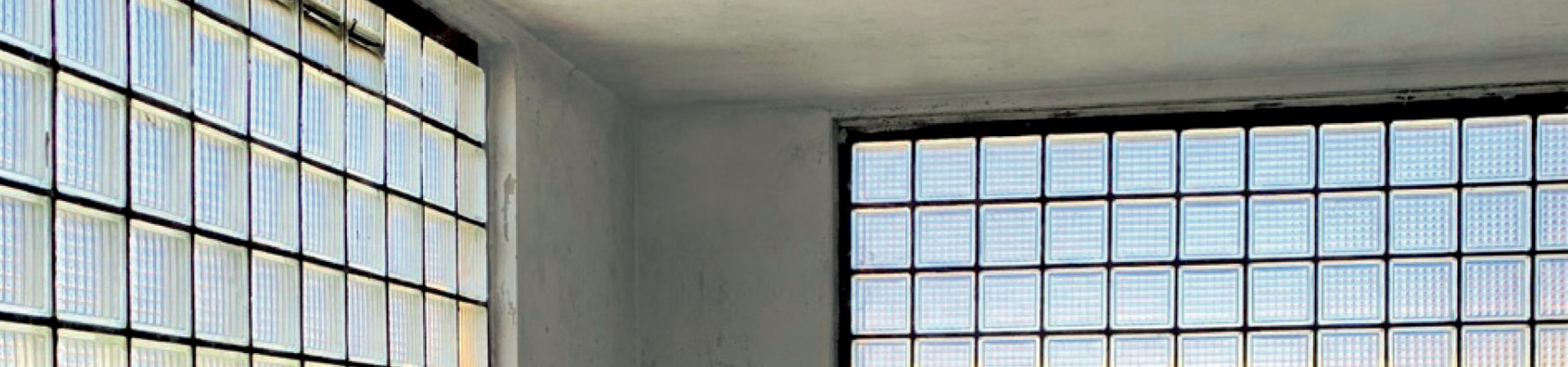 Graue Wand mit historischen Fenstern aus Glasbausteinen